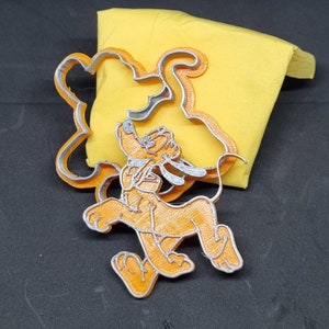 Könnte beinhalten: Ein 3D-gedruckter Ausstecher in Form eines laufenden Cartoon-Hundes. Der Ausstecher ist orange und silber.