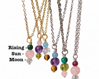 May include: Six necklaces with gold and silver chains, each featuring three stacked crystal beads. Text reads: Big 3 Zodiac Crystal Necklaces, Rising, Sun, Moon. The beads vary in colour, including green, pink, clear, purple, yellow, blue, and brown.