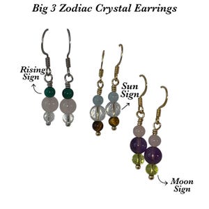 May include: Big 3 Zodiac Crystal Earrings. Three pairs of earrings with various colored crystal beads. The earrings are labeled "Rising Sign", "Sun Sign", and "Moon Sign". The text is in black cursive font.