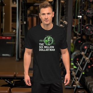 May include: Black t-shirt featuring a green graphic of a man in a futuristic suit with the text "THE SIX MILLION DOLLAR MAN".