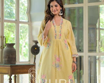 May include: A light yellow embroidered tunic and matching pants set. The tunic features floral embroidery and lace trim. The pants have matching embroidery along the hem. The outfit is part of the "SHUBH FASHION" collection.