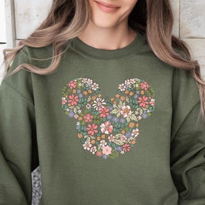 May include: A green sweatshirt with a floral design in the shape of Mickey Mouse's ears.