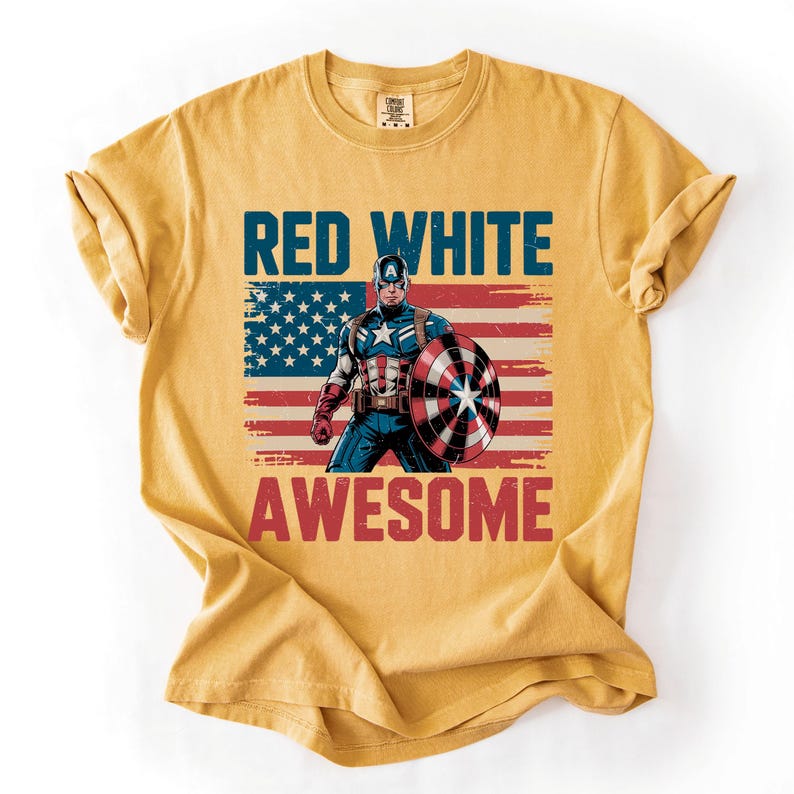 A yellow t-shirt with a graphic design featuring a superhero character and the text "RED WHITE AWESOME" printed on it.