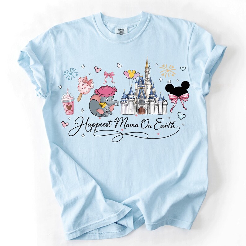 A light blue t-shirt with a Disney-themed design, including a castle, Mickey Mouse, and other Disney characters. The text on the t-shirt says "Happiest Mama On Earth".