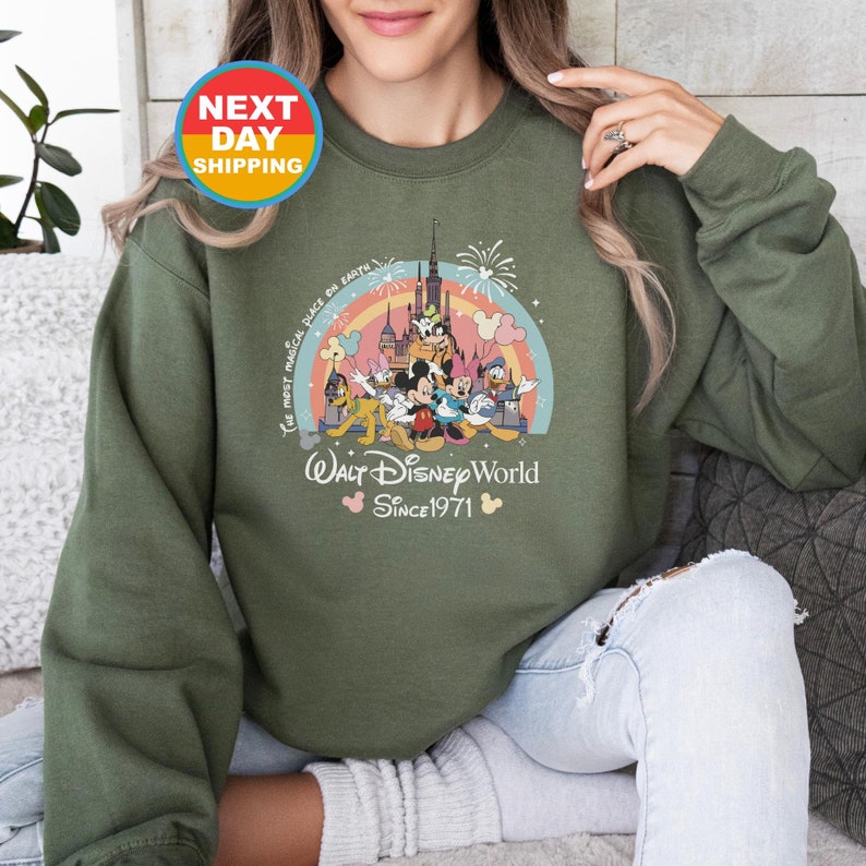 May include: Green sweatshirt with a vintage-style graphic of Mickey Mouse and friends in front of the Cinderella Castle. The text reads "The most magical place on Earth" and "Walt Disney World Since 1971".