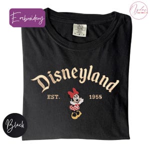 A black t-shirt with the text "Disneyland EST. 1955" and a Minnie Mouse embroidered on it.