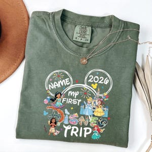 A green t-shirt with a Disney-themed design, including characters from the Disney film series, printed on it.
