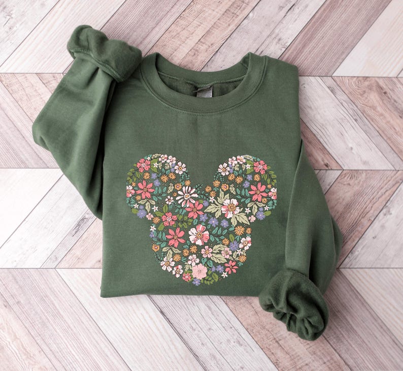 May include: A green sweatshirt featuring a floral Mickey Mouse design. The flowers are in shades of pink, yellow, and green.