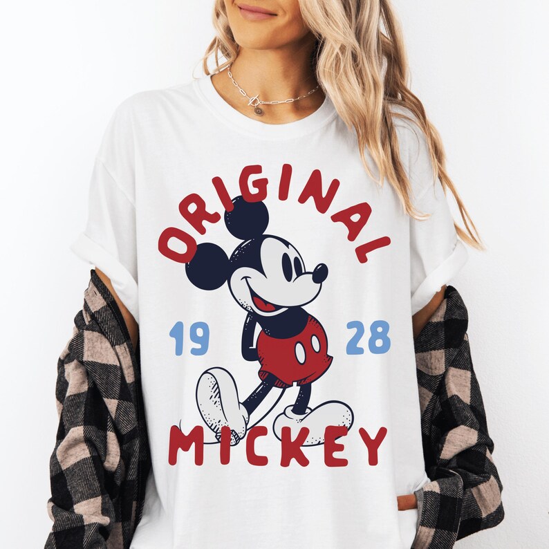 A woman wearing a white t-shirt with a graphic of Mickey Mouse and the text "ORIGINAL MICKEY" printed on it.