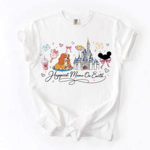 A white t-shirt with a Disney-themed design featuring Lady and the Tramp, a castle, and various Disney-related elements.