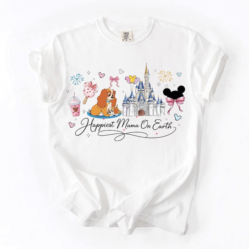 A white t-shirt with a Disney-themed design featuring Lady and the Tramp, a castle, and various Disney-related elements.