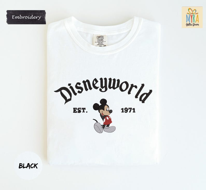 A white t-shirt with the text "Disneyworld" and "EST. 1971" printed on it, along with a Mickey Mouse graphic.