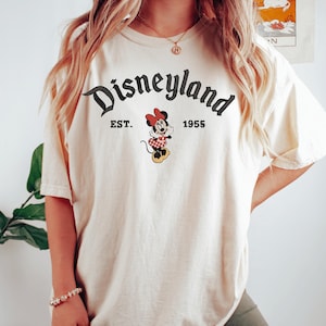 A person wearing a white t-shirt with the text "Disneyland EST. 1955" and a Minnie Mouse graphic.
