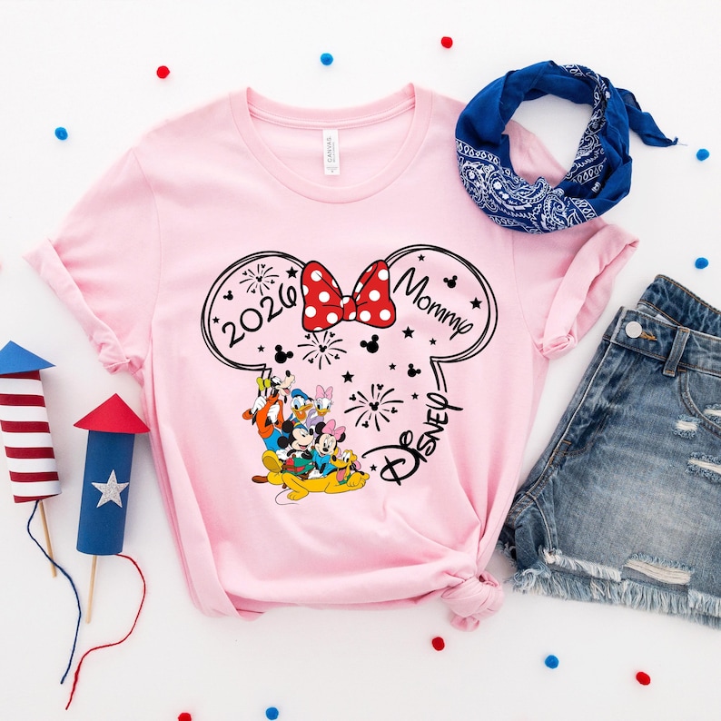a pink t-shirt with a Disney-themed design, a blue bandana, denim shorts, and a fireworks-themed sparkler.