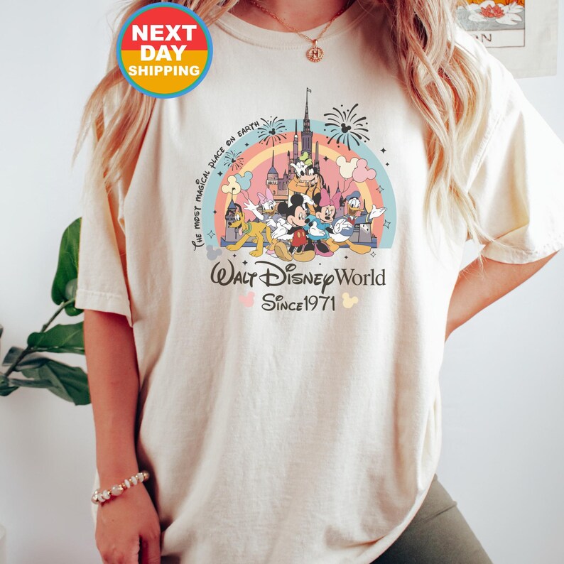 May include: A white t-shirt with a colorful graphic of Mickey Mouse and friends in front of the Walt Disney World castle. The text "The Most Magical Place on Earth" and "Walt Disney World Since 1971" are printed on the shirt.