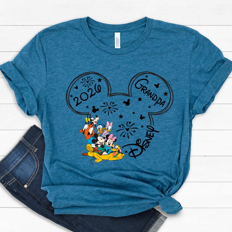 A blue t-shirt with a graphic design featuring Disney characters and the text "2020 Grandpa Disney" printed on it.