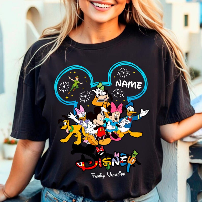 A woman wearing a black t-shirt with a colorful graphic of Disney characters and the text "Disney Family Vacation" printed on it.