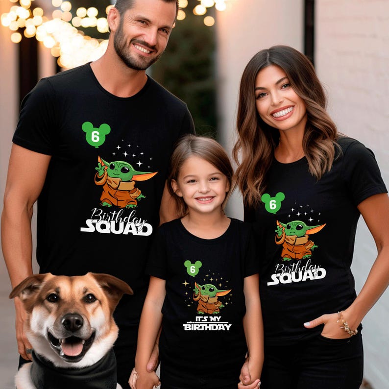 A family of three, consisting of a man, a woman, and a young girl, posing together in front of a building with Christmas lights in the background.