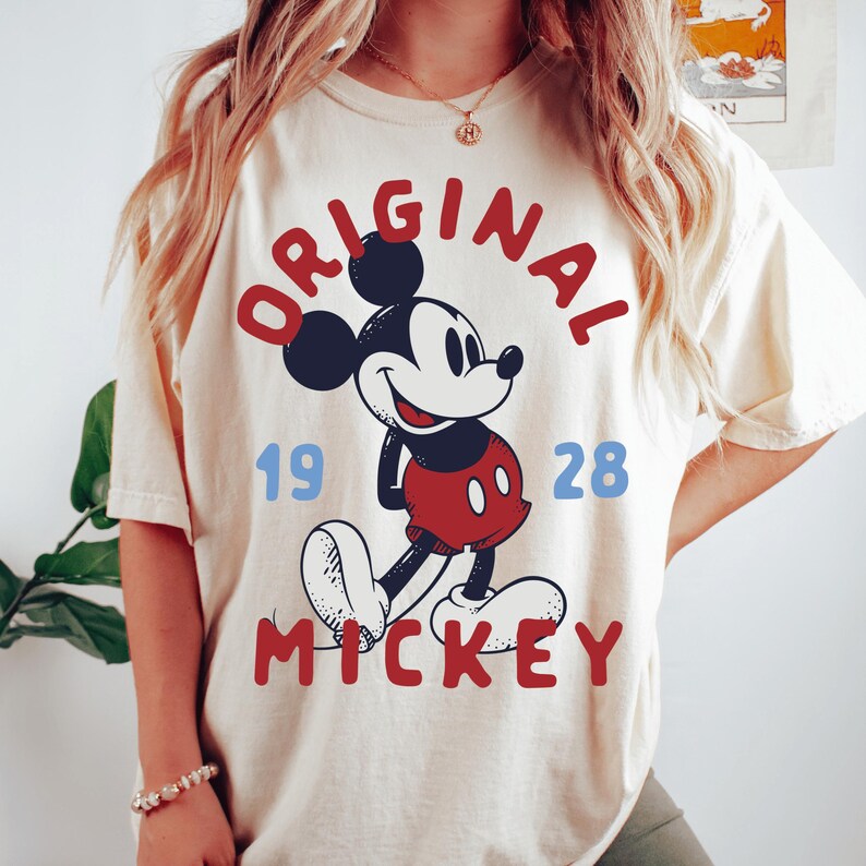 A woman wearing a white t-shirt with a graphic of Mickey Mouse and the text "ORIGINAL MICKEY" printed on it.