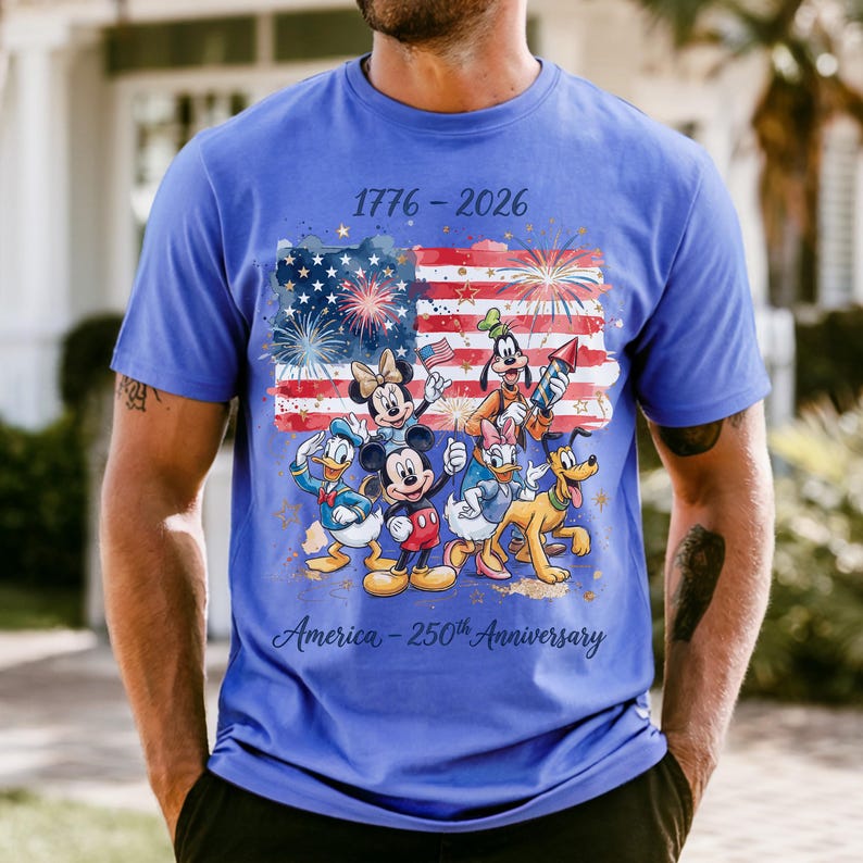 A man wearing a blue t-shirt with a graphic design featuring Disney characters and fireworks.