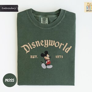 a green t-shirt with a Mickey Mouse design and text that reads "Disneyworld EST. 1971".