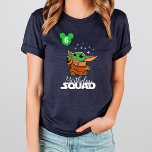 A woman wearing a dark blue t-shirt with a graphic of a cartoon character and text that says "Birthday Squad" printed on it.