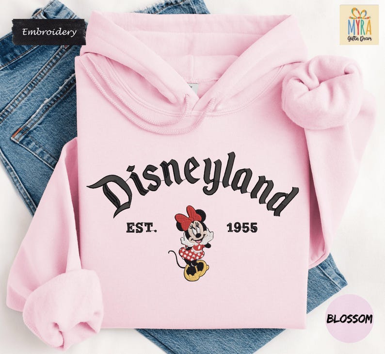 A pink hoodie with the text "Disneyland EST. 1955" and a Minnie Mouse graphic, along with a pair of blue jeans.