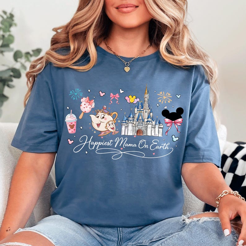 A woman wearing a blue t-shirt with a Disney-themed design, including a castle, Mickey Mouse, and other Disney characters.