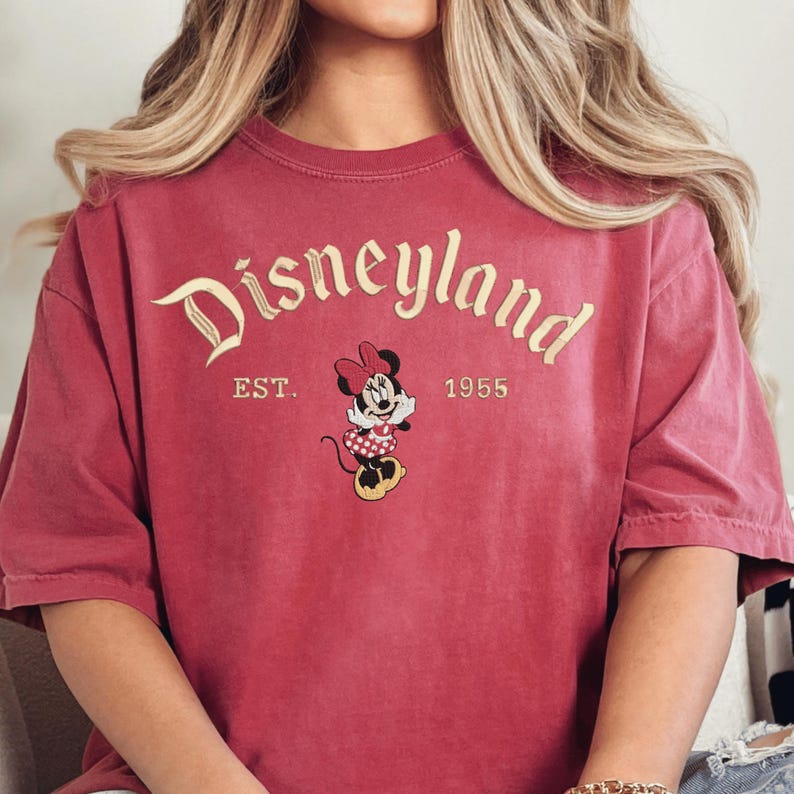 A person wearing a red t-shirt with the text "Disneyland EST. 1955" and a Minnie Mouse graphic.