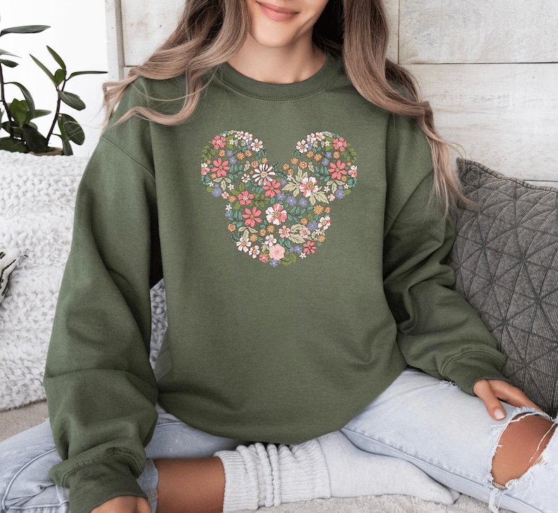 May include: A green sweatshirt with a floral design in the shape of Mickey Mouse's ears.