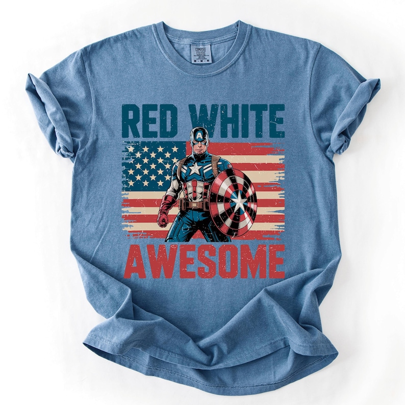 A blue t-shirt with a graphic design featuring a superhero character and the text "RED WHITE AWESOME" printed on it.