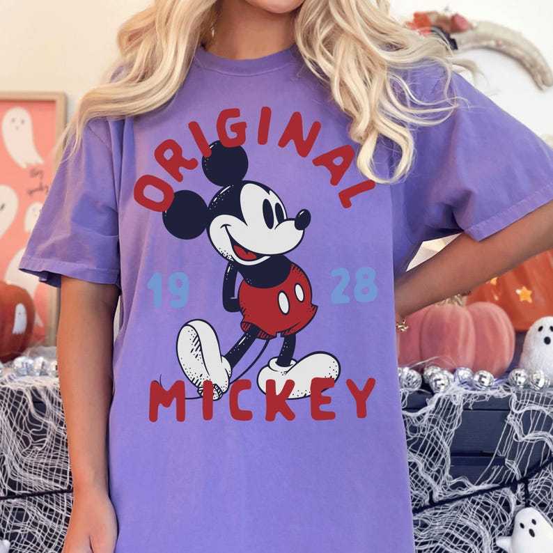 A person wearing a purple t-shirt with a Mickey Mouse graphic and text.