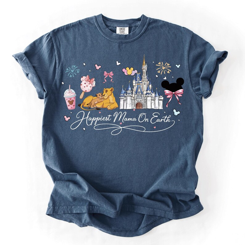 A blue t-shirt with a graphic design featuring a castle, Mickey Mouse, and other Disney-themed elements, along with the text "Happiest Mama On Earth".