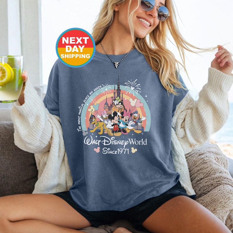 May include: A blue t-shirt with a colorful graphic of Mickey Mouse and friends in front of Cinderella's Castle. The text "The most magical place on Earth" and "Walt Disney World Since 1971" are printed on the shirt.