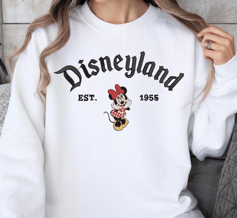 A white sweatshirt with the text "Disneyland EST. 1955" and an image of Minnie Mouse, a character from the Disney theme park.