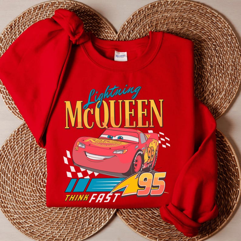 A red t-shirt with a Lightning McQueen graphic and the text "Think Fast" printed on it, along with a wicker placemat underneath.