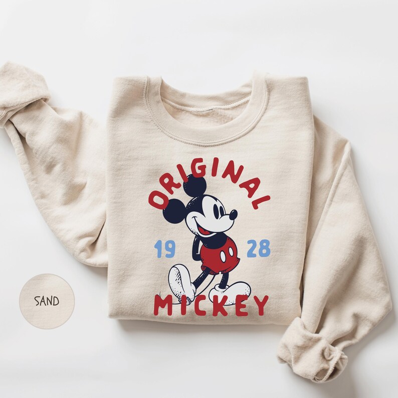 A beige sweater with a graphic of Mickey Mouse and text that reads "ORIGINAL" and "1928" printed on it.