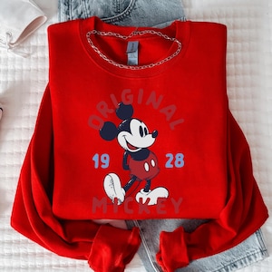 A red sweatshirt with a Mickey Mouse design and the text "ORIGINAL" and "19 28" printed on it.