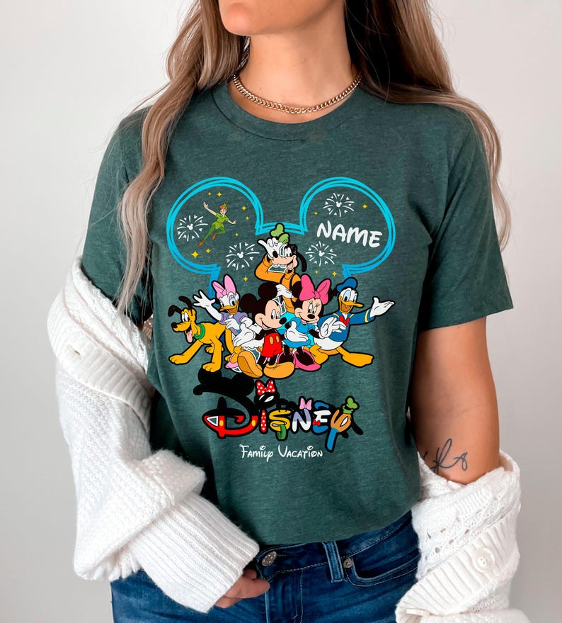 A woman wearing a green t-shirt with a Disney character design and the text "Disney Family Vacation" printed on it.