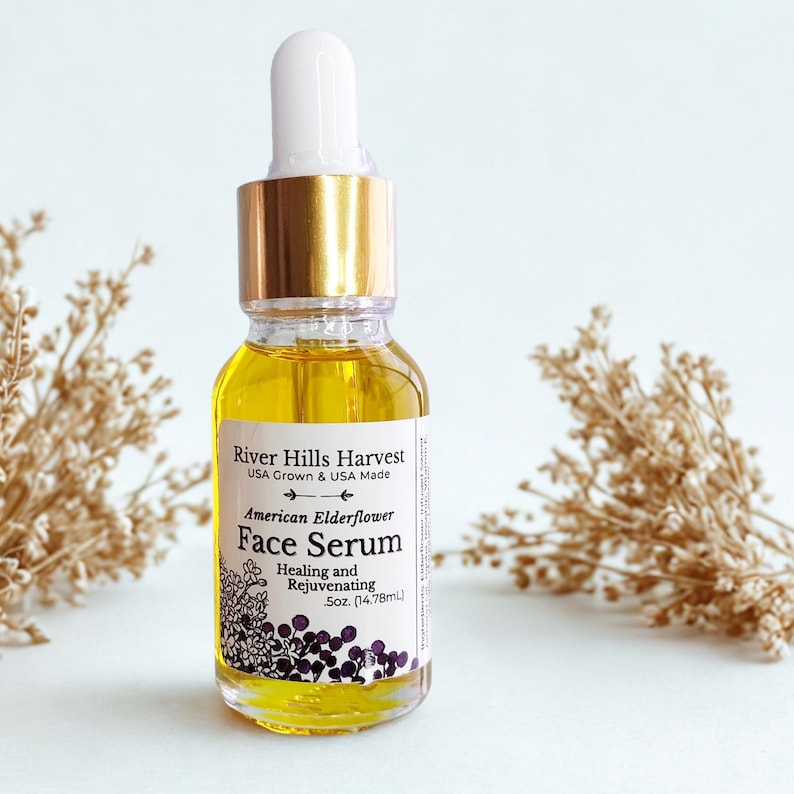 May include: A clear glass bottle of face serum with a gold cap and white dropper. The label reads "River Hills Harvest American Elderflower Face Serum." The serum is a golden yellow color. The bottle contains 5oz (14.78ml) of product.