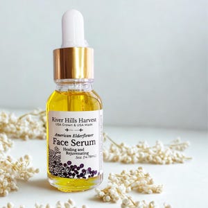 May include: A small glass bottle of American Elderflower Face Serum. The bottle has a gold cap and a white dropper. The label reads "River Hills Harvest" and "Healing and Rejuvenating". The bottle contains 0.5 oz (14.78ml) of serum.