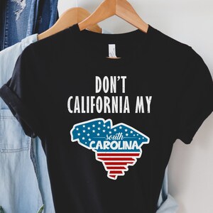 May include: Black t-shirt with white text that reads "Don't California My South Carolina" and a red, white and blue outline of the state of South Carolina.