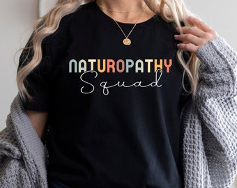 May include: A black t-shirt with the text "Naturopathy Squad" in rainbow colors. The text is in a retro style font.