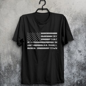 May include: Black t-shirt with a distressed American flag design and the text "TRY THAT IN A SMALL TOWN".