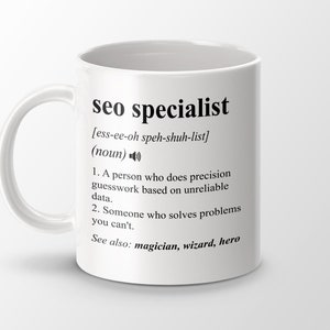 Może przedstawiać: Biały kubek ceramiczny z czarno-białym wzorem. Kubek zawiera definicję terminu "specjalista SEO" z humorystycznym opisem. Tekst brzmi: "specjalista SEO [ess-ee-oh speh-shuh-list] (rzeczownik) 1. Osoba, która dokonuje precyzyjnych przypuszczeń na podstawie niewiarygodnych danych. 2. Ktoś, kto rozwiązuje problemy, których nie możesz rozwiązać. Zobacz także: magik, czarodziej, bohater"