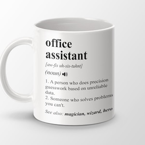 Pode incluir: Caneca de cerâmica branca com um design preto que define a palavra "assistente de escritório" e sua pronúncia. A definição inclui dois marcadores e a frase "Veja também: mágico, mago, herói".