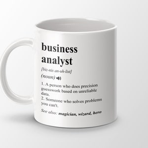 Peut inclure: Une tasse à café en céramique blanche avec un graphique noir qui définit un "analyste d'affaires" comme une personne qui fait des estimations précises basées sur des données peu fiables et qui résout des problèmes que vous ne pouvez pas résoudre. Le texte comprend également "Voir aussi : magicien, sorcier, héros."