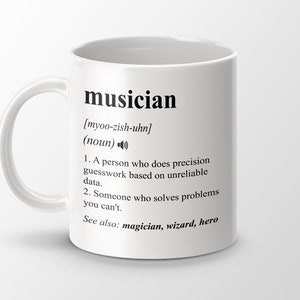 May include: White ceramic coffee mug with a black definition of the word "musician" printed on it. The definition includes the pronunciation, part of speech, and two definitions. The mug has a black handle.