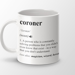 Op de afbeelding: Een witte keramische mok met een zwarte definitie van het woord "coroner" erop gedrukt. De definitie luidt: "/'kərənər/ (zelfstandig naamwoord) 1. Een persoon die voortdurend problemen oplost waarvan je niet eens wist dat ze bestonden - op een manier die je niet begrijpt. (zie ook: tovenaar, tovenaar, held)"