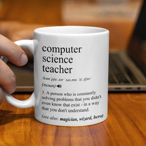 Puede incluir: Taza de cerámica blanca con una definición en blanco y negro de "profesor de informática" impresa en ella. La definición dice: "Una persona que constantemente resuelve problemas que ni siquiera sabías que existían, de una manera que no entiendes. (ver también: mago, mago, héroe)"